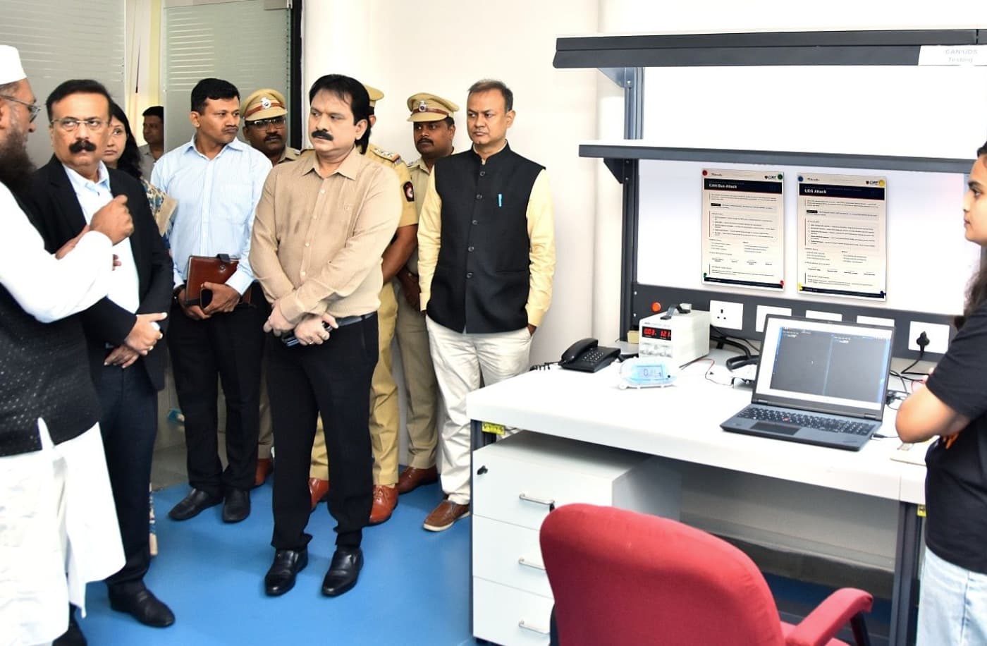 A live demonstration at the Automotive Cybersecurity Penetration Testing Laboratory: a bench carrying a laptop running CAN analysis, a bench power supply, and printed CAN Bus Attack and UDS Attack procedure sheets.